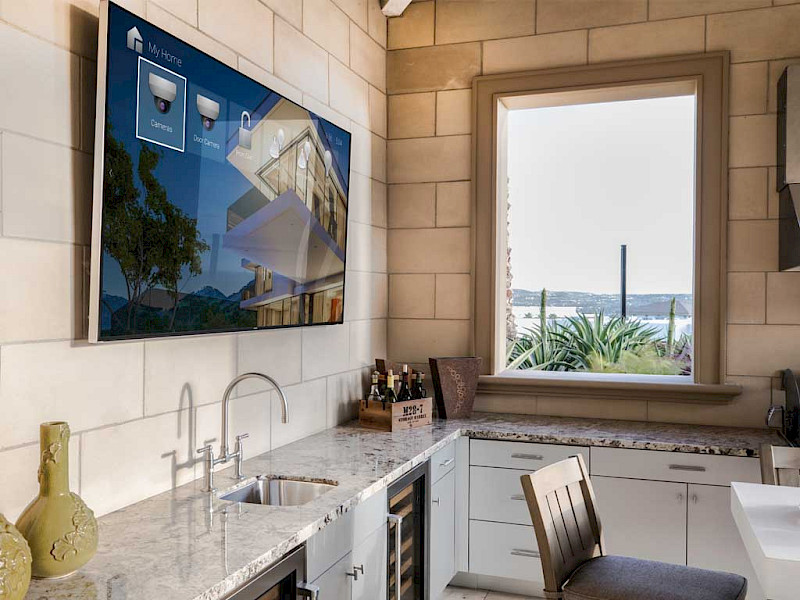 flat screen tv mounted in a kitchen with security camera and smart lighting control apps
