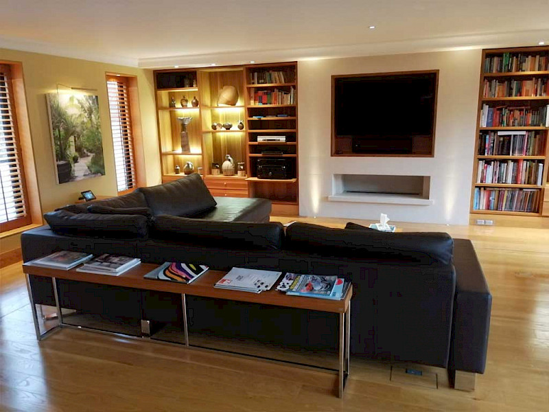 media room with tv on the wall in front of  a large black sofa