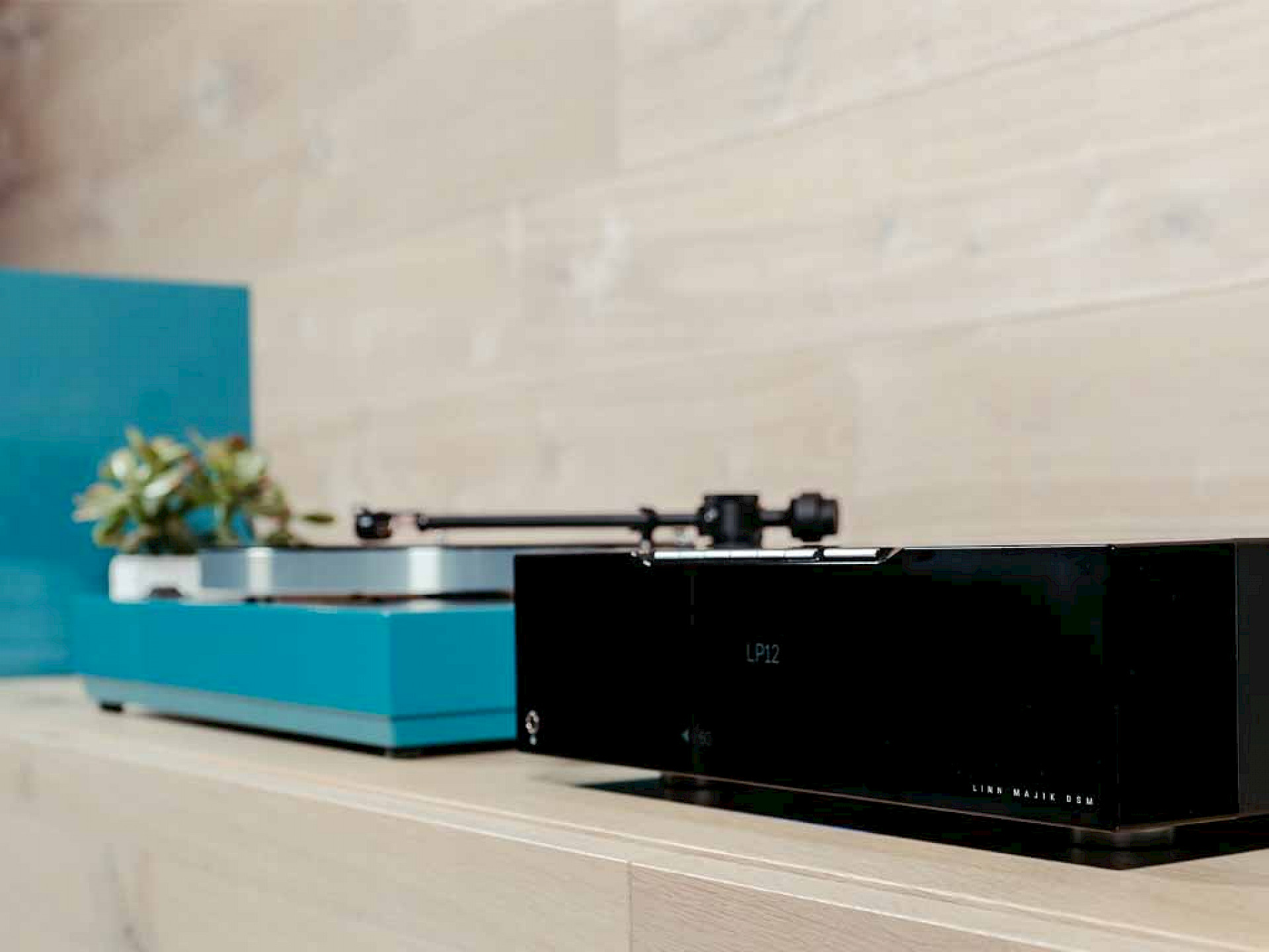 Linn Majik DSM next to blue Linn LP12 on a wooden shelf