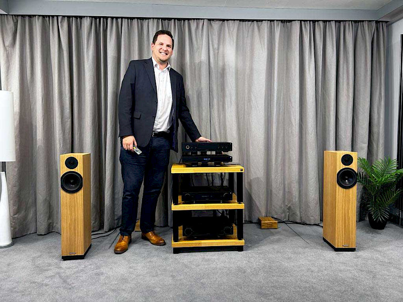 staurt hoad from arcam stood next to arcam radia range with walnut coloured spendor a4 speakers either side